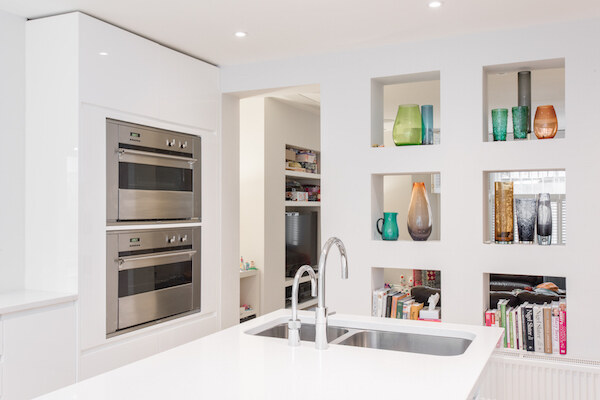 Contemporary white kitchen with twin stainless ovens and built-in display cubbies