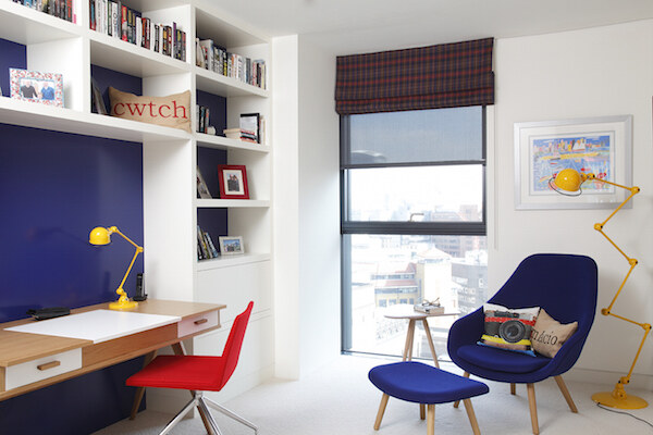Bespoke home study with blue accent wall, shelving and yellow lamp
