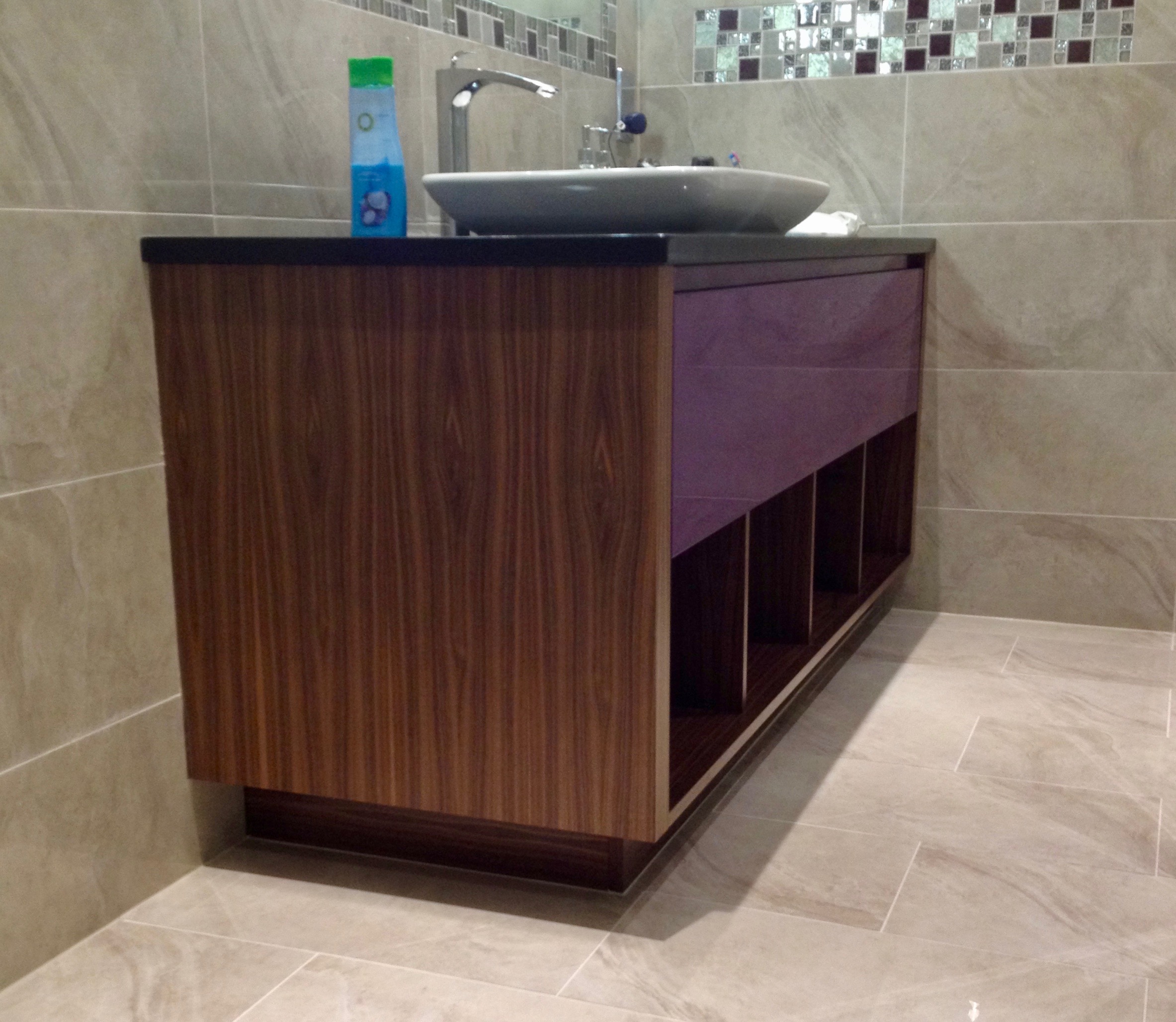 Bespoke walnut bathroom vanity unit with black granite top, vessel sink and open lower shelving